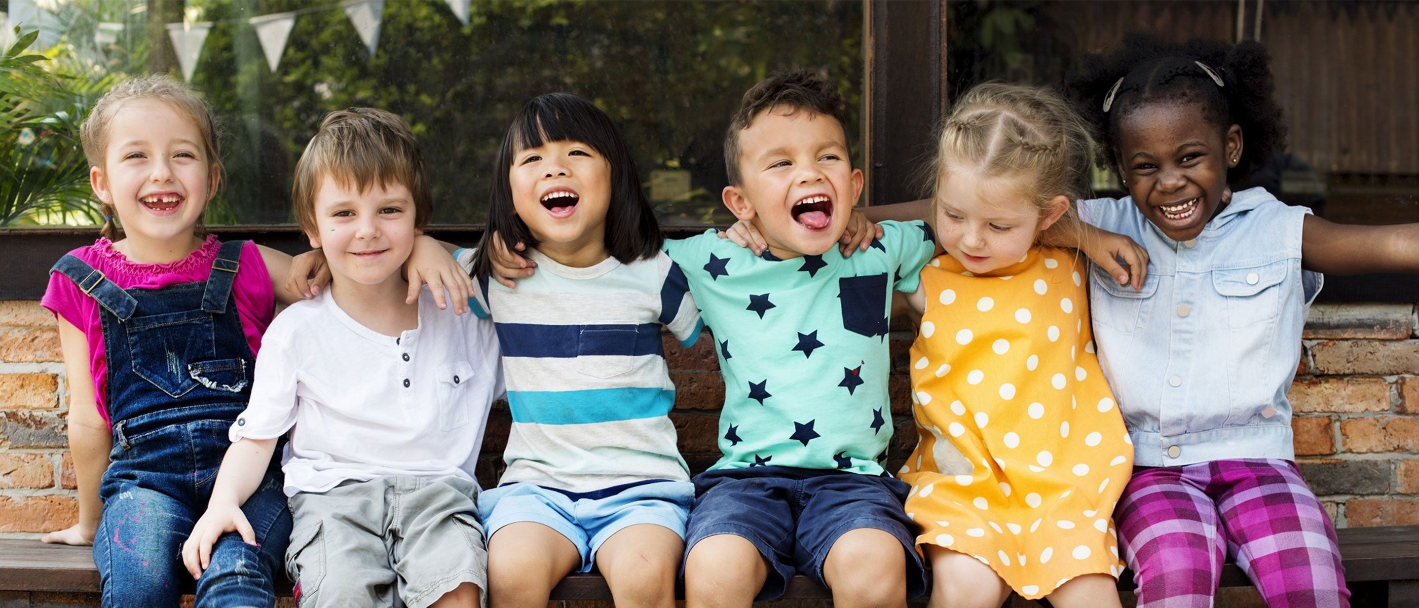Kinder sitzen lachend auf einer Bank