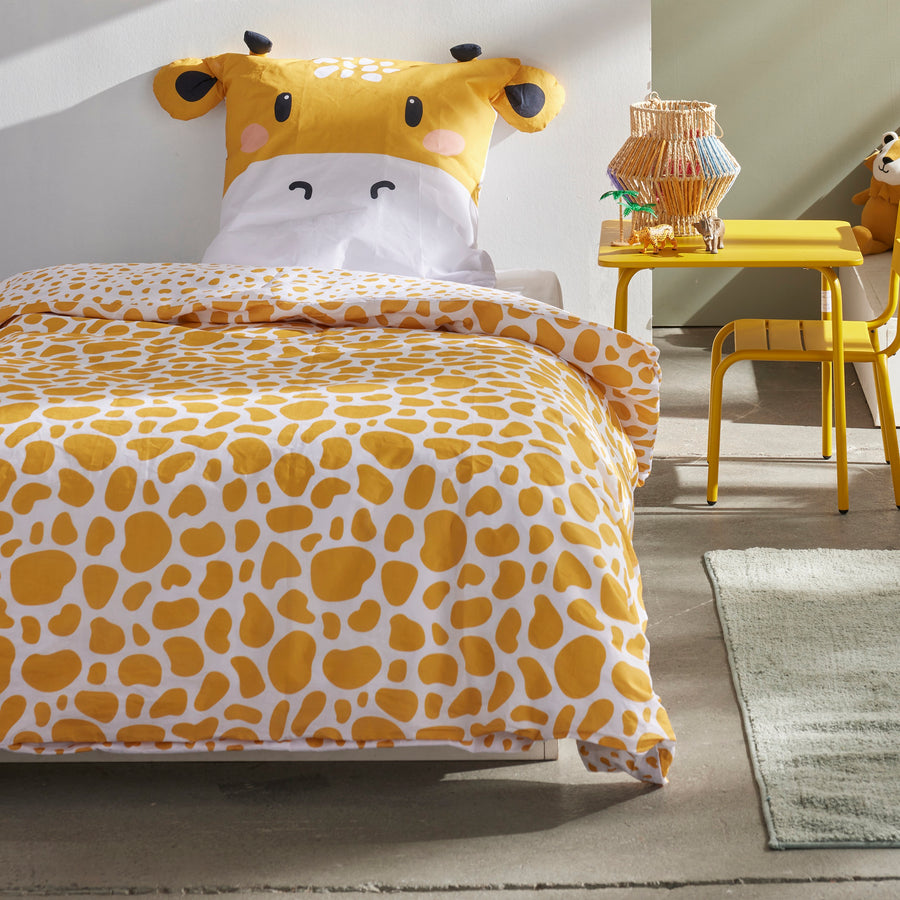 Bettwäsche gelb mit Giraffenkopf als Kopfkissen mit Ohren und Hörnern und gemusterter Bettdecke auf Bette gezogen