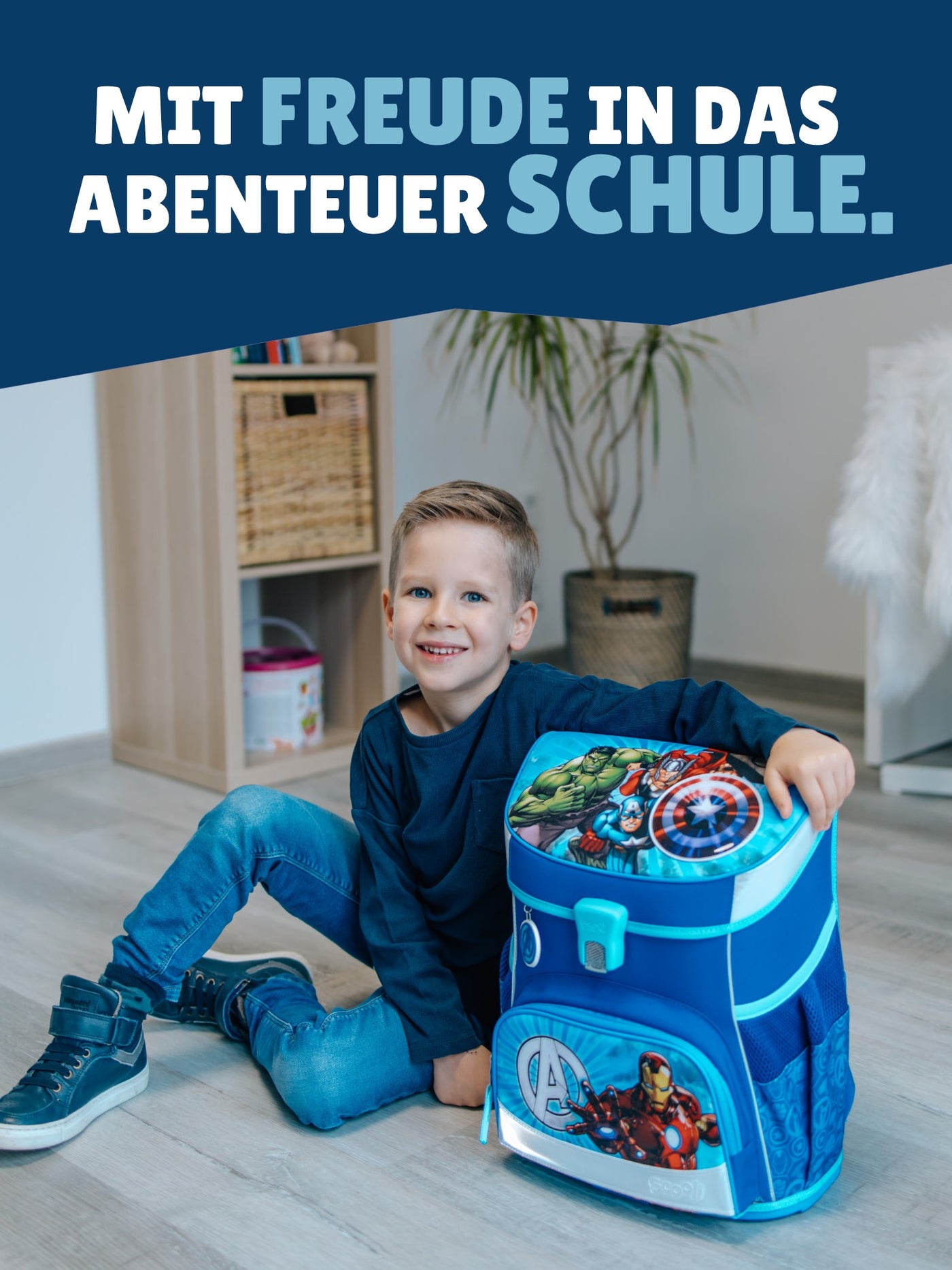 Kleiner Jungen sitzt stolz neben seinem Avengers Schulranzen - Spruch "Mit Freude in das Abenteuer Schule"