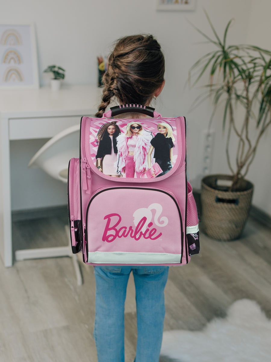 Mädchen steht in einem Wohnzimmer mir Barbie Schulranzen auf dem Rücken