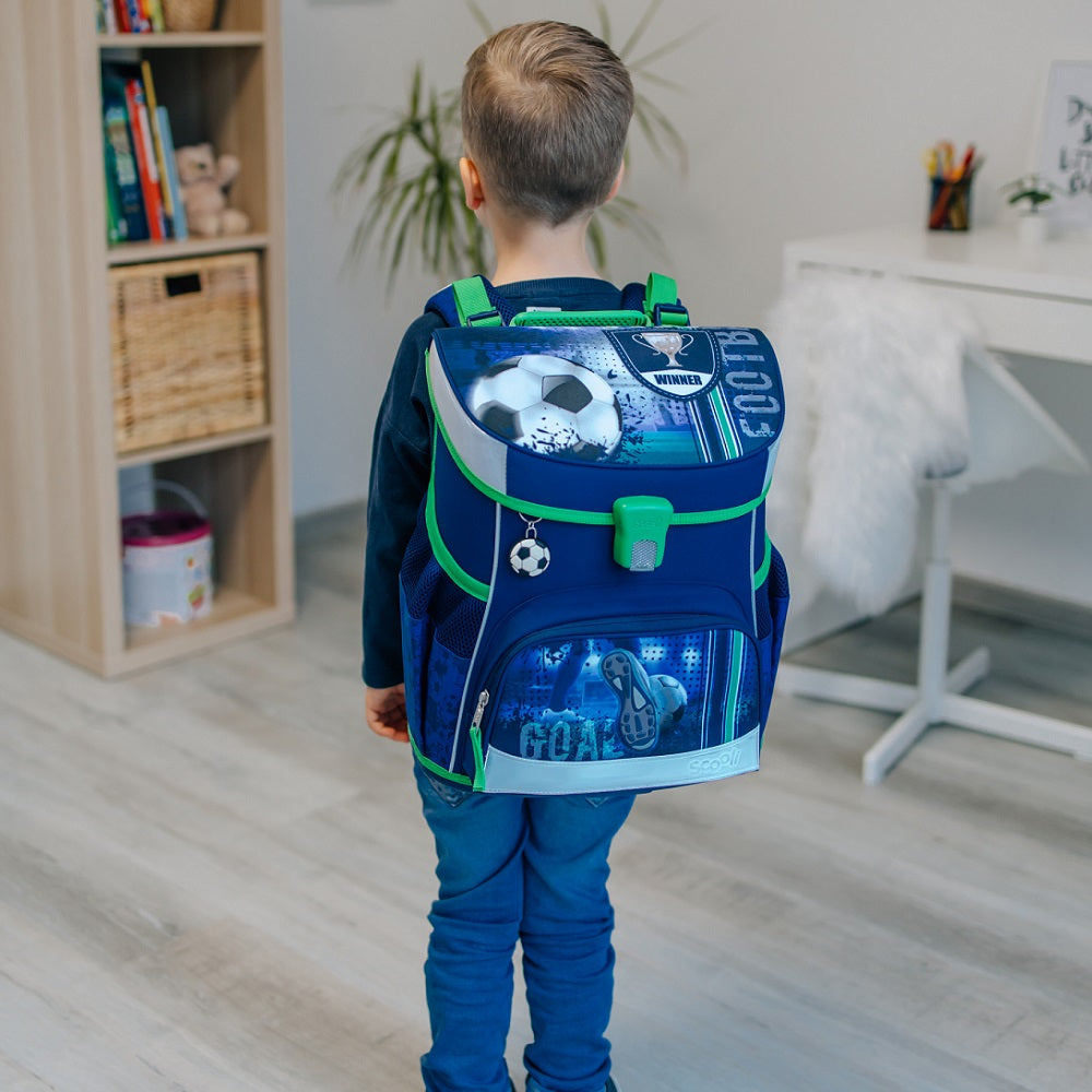 Junge trägt Schulranzen am Rücken in Wohnzimmer