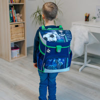 Junge trägt Schulranzen am Rücken in Wohnzimmer