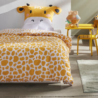 Bettwäsche gelb mit Giraffenkopf als Kopfkissen mit Ohren und Hörnern und gemusterter Bettdecke auf Bette gezogen