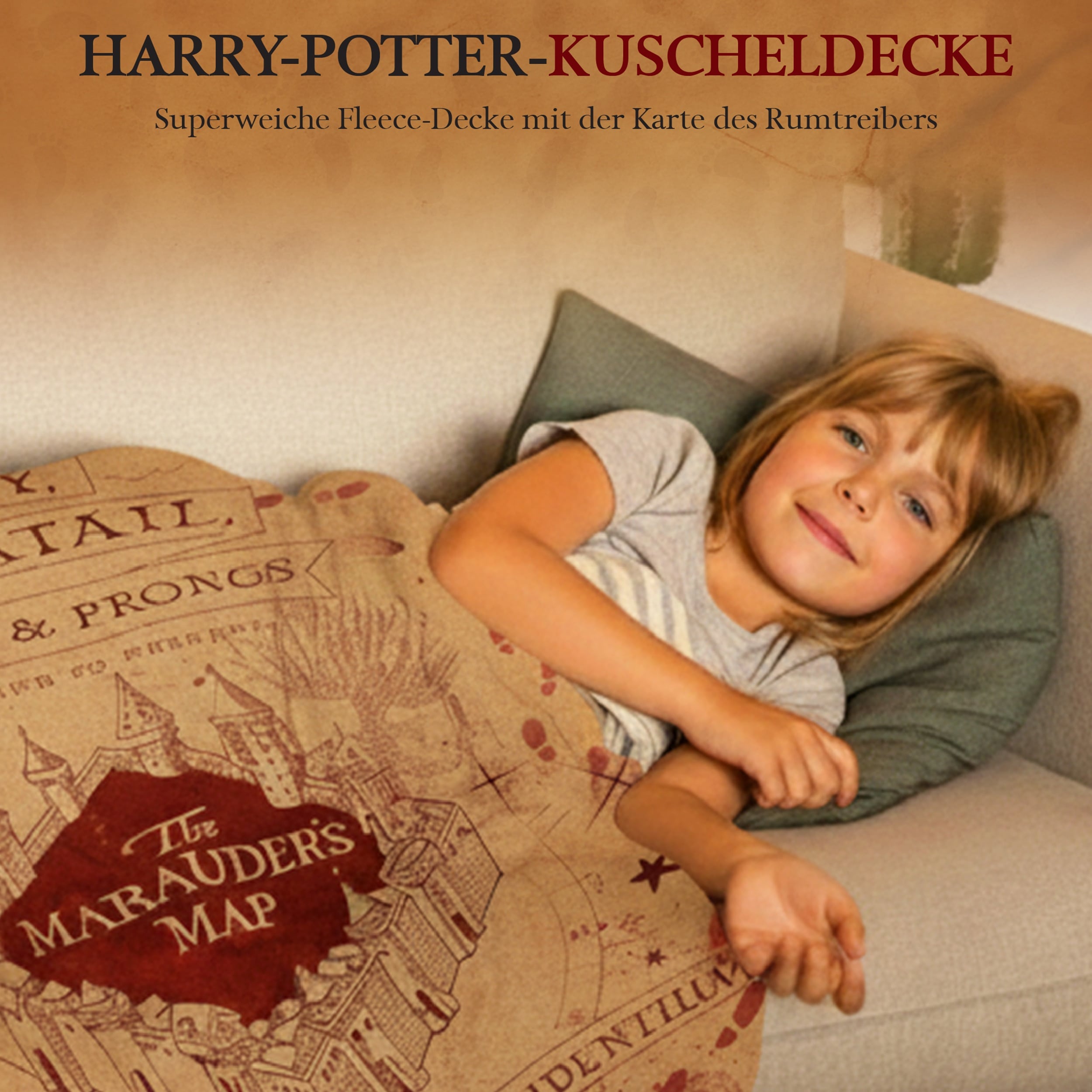 Kind liegt lächend auf der Couch in Harry Potter Decke gehüllt
