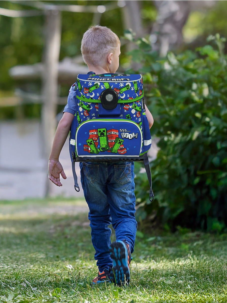 Junge läuft mit blauem Minecraft Schulranzen durch den Park