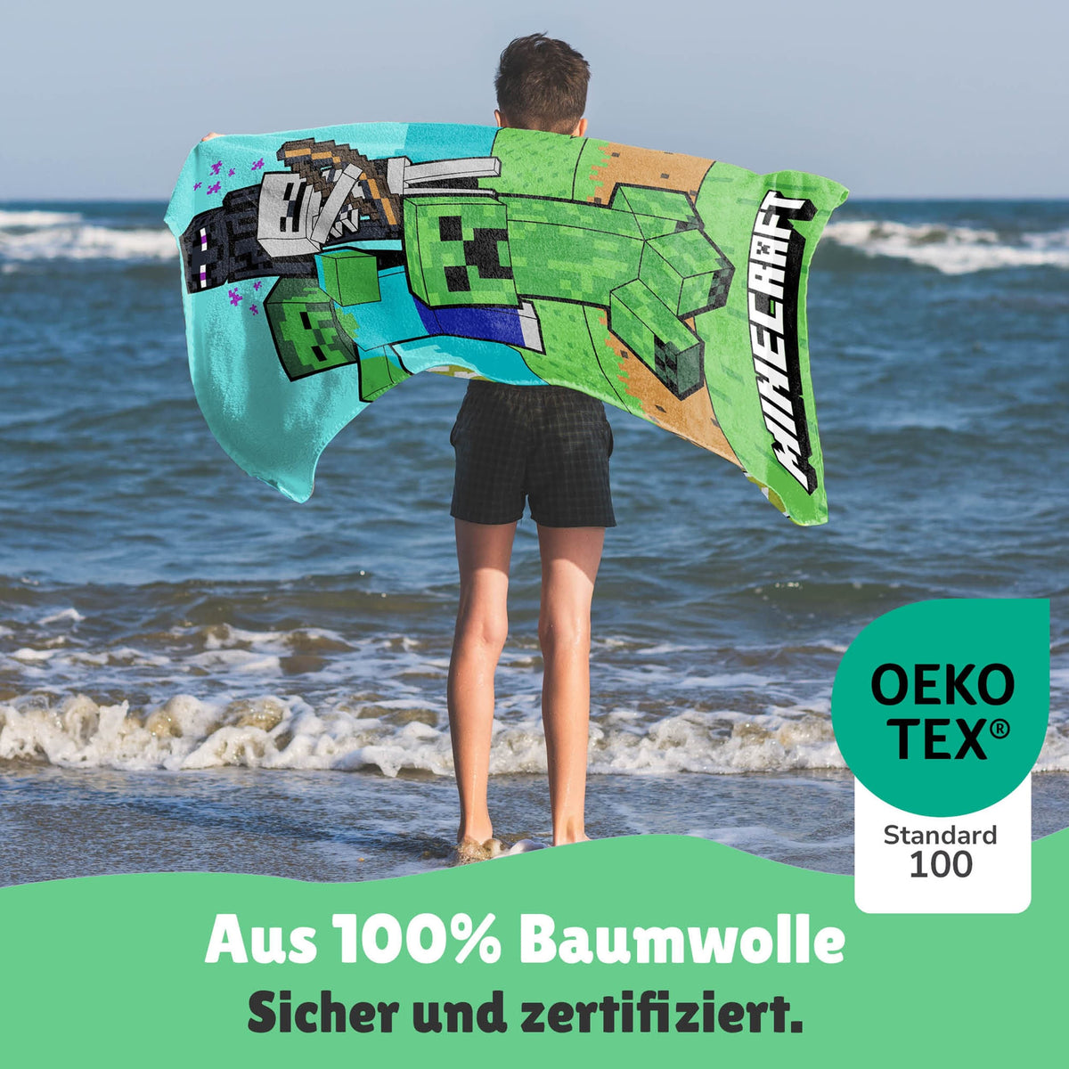 Junge hat das Handtuch über die Schultern geworden und steht am Meer
