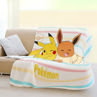 Kuscheldecke mit Pikachu und Evoli vor weißem grund mit bunten Streifen über Couch geworfen