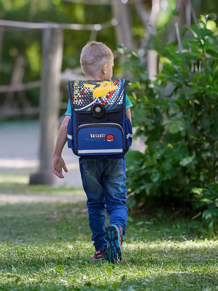 Junge läuft mit blauem Pokemon Schulranzen auf Spielplatz