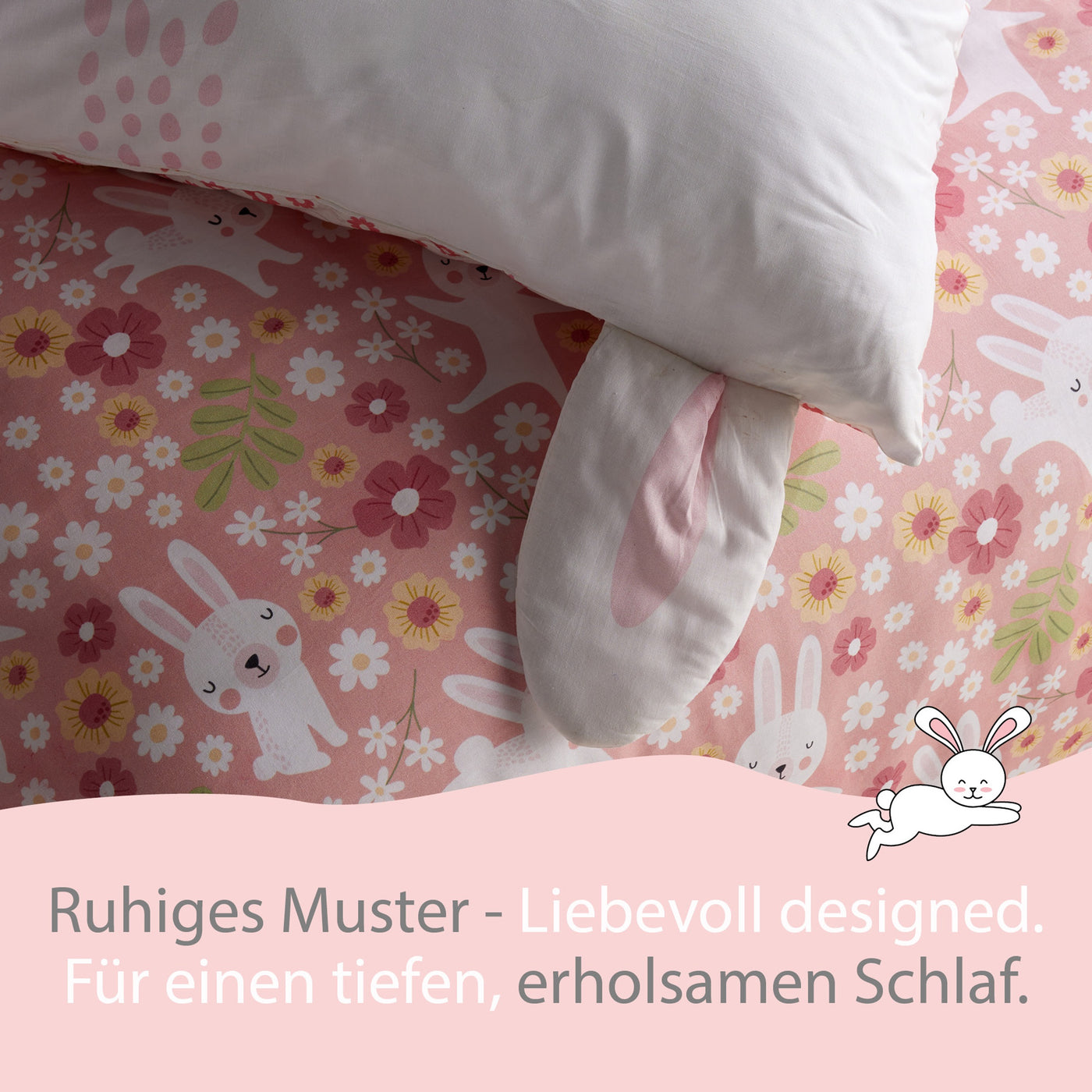 Großaufnahme Kopfkissen mit Ohren und Bettdecke mit rosa Hasen und Blumen Muster darunter