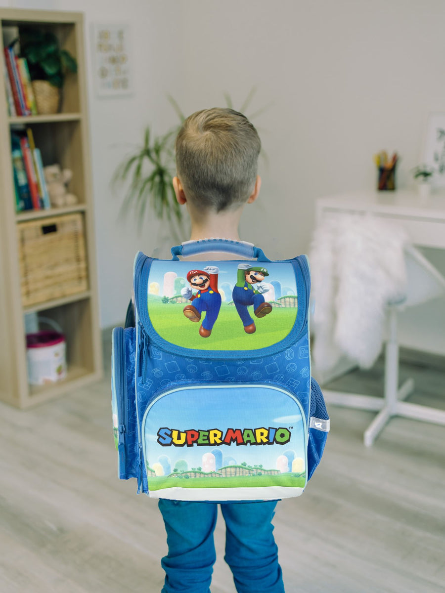 Junge steht vor Schule mit Super Mario Schulranzen auf dem Rücken bereit für seinen 1. Tag