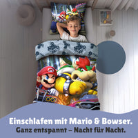 Junge schläft seelig lächeln in Super Mario Kart Bettwäsche in seinem Kinderzimmer im Bett