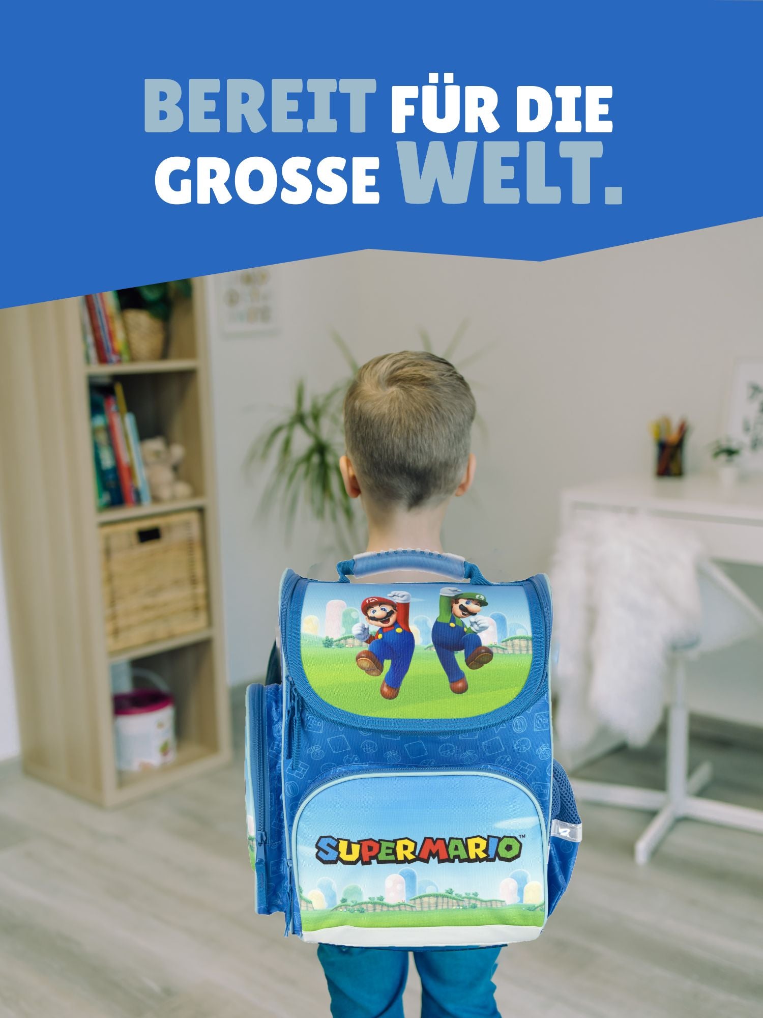 Junge steht in hellem Wohnzimmer und trägt den blau grünen Super Mario Schulranzen auf dem Rücken - Spruch "Bereit für die grosse Welt"