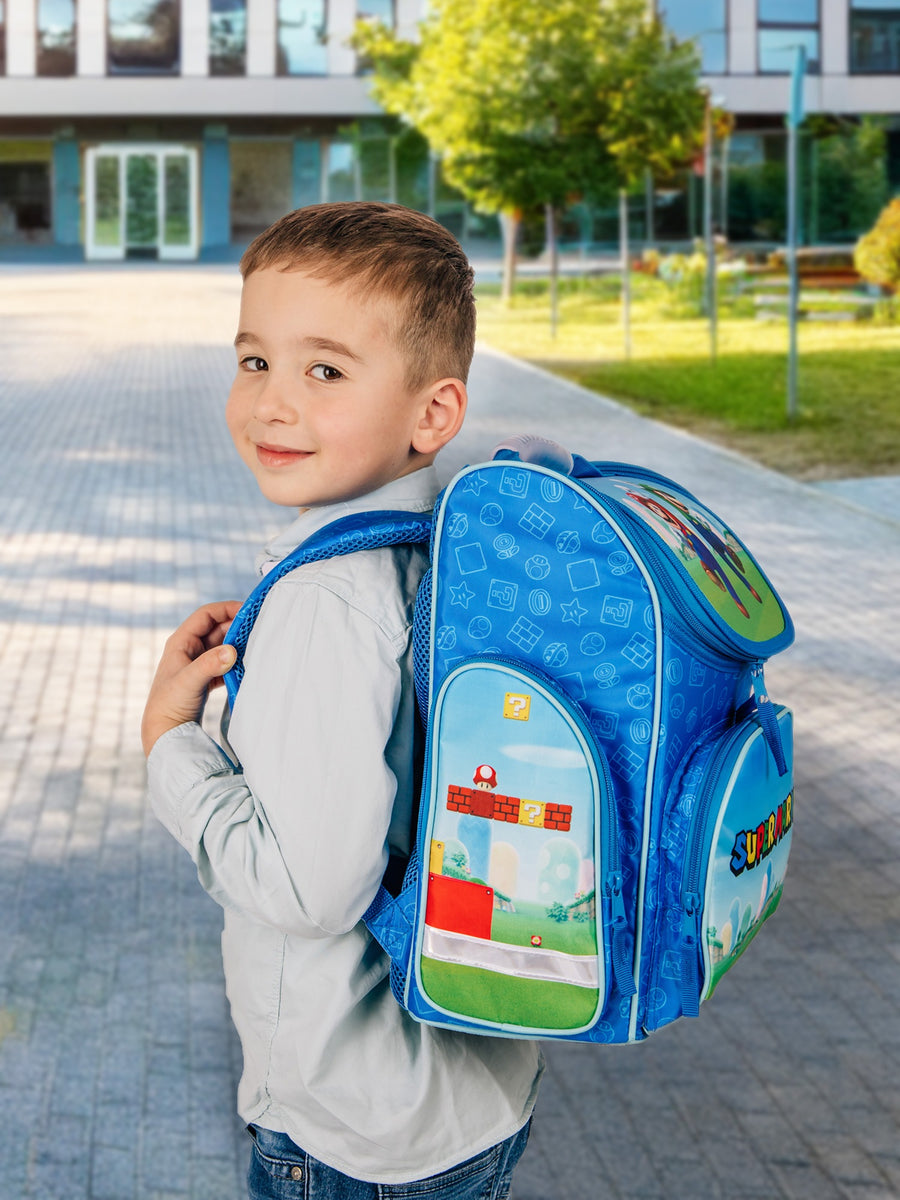 Junge steht vor Schule mit Super Mario Schulranzen auf dem Rücken bereit für seinen 1. Tag
